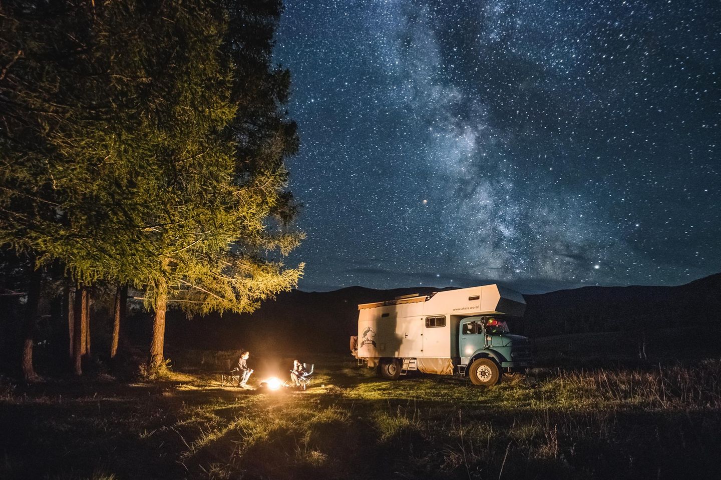 Familie mit Camping-Truck sitzt am Lagerfeuer im russichen Altai