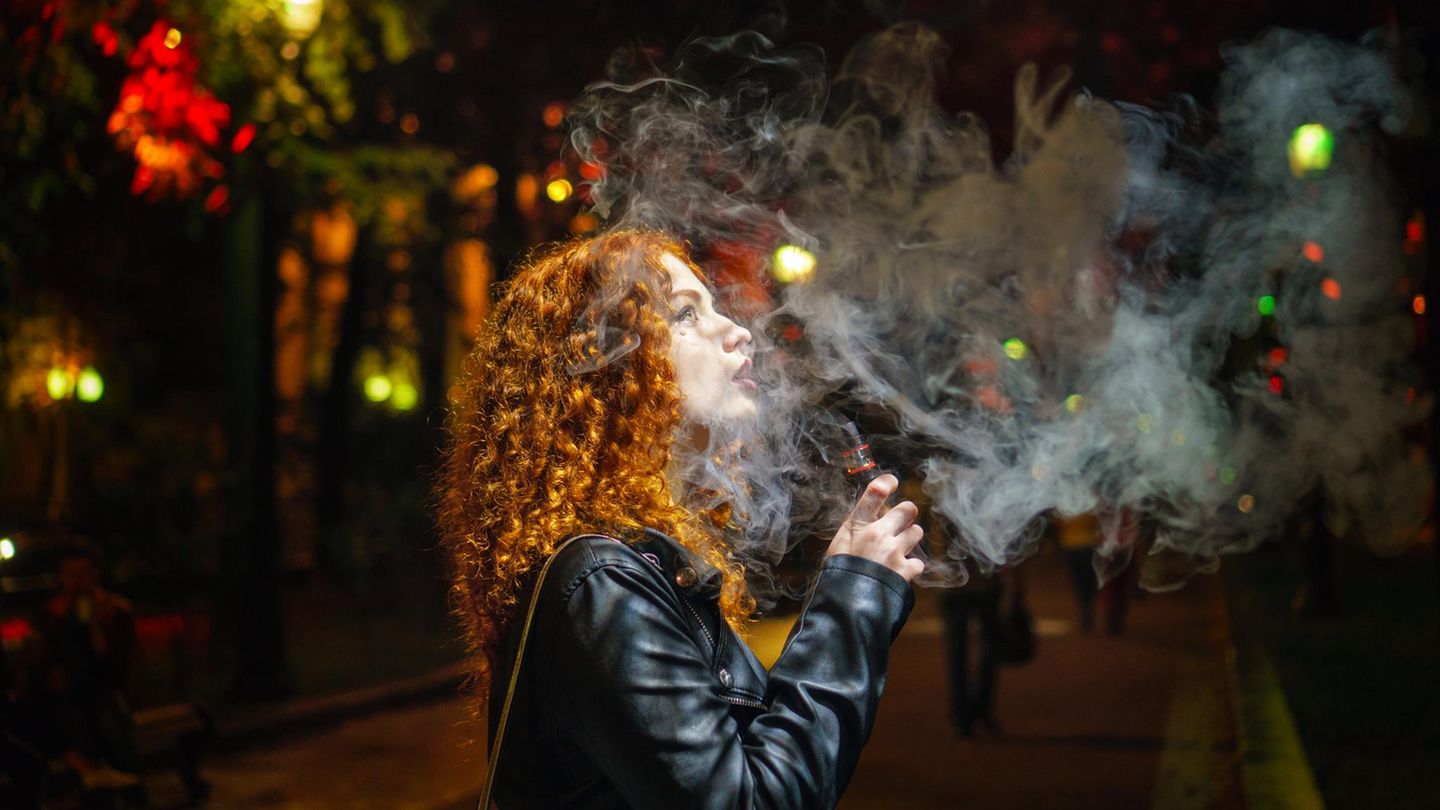 Rauchverbot: Eine junge Frau mit roten Locken raucht nachts eine Zigarette