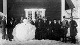 Gruppe von Menschen posiert um Schneemann