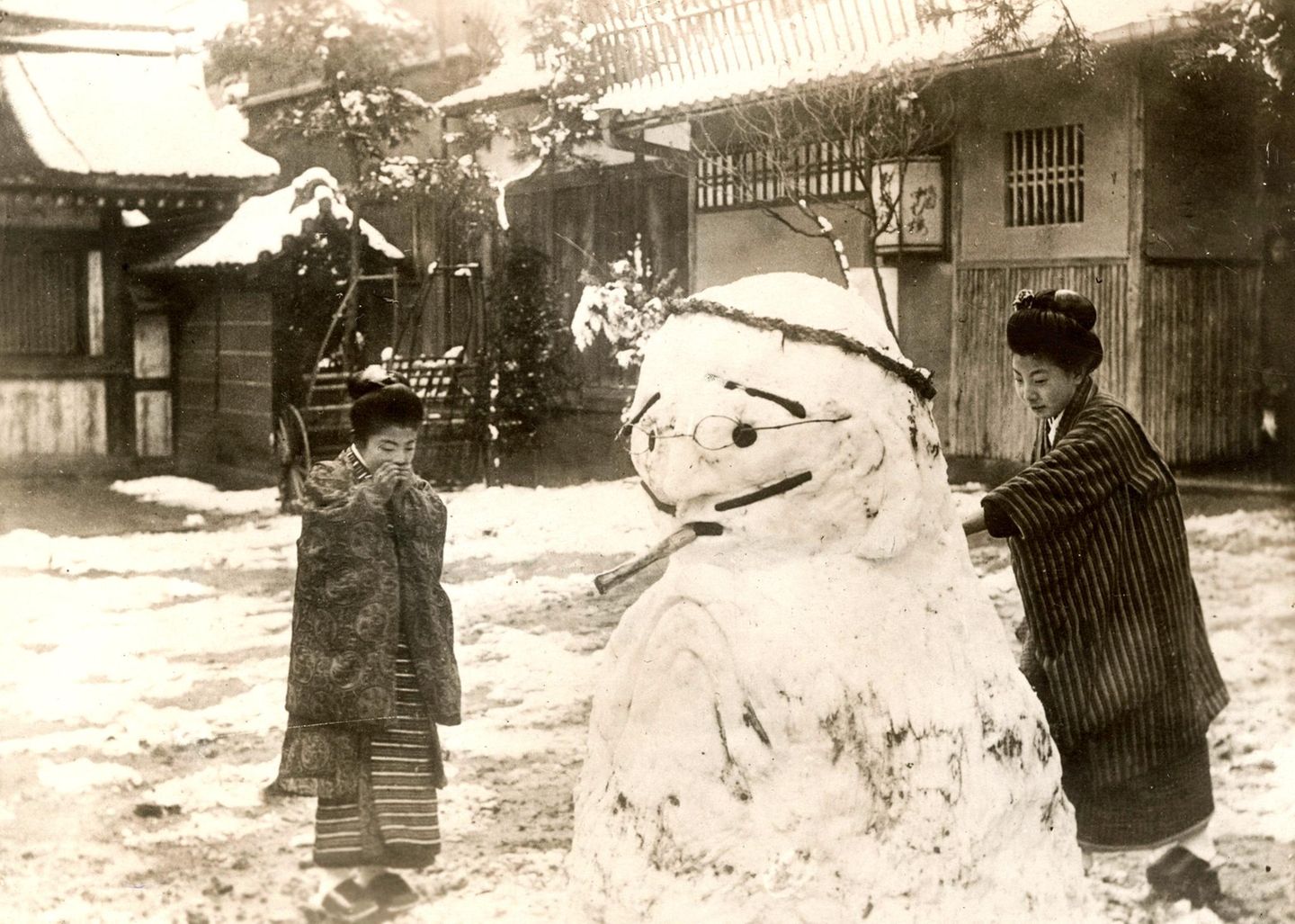 Zwei Japanerinnen bauen Schneemann