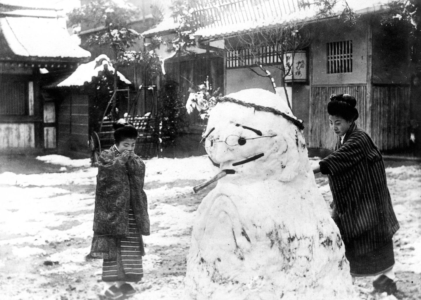 Zwei Japanerinnen bauen Schneemann