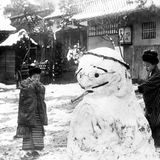 Zwei Japanerinnen bauen Schneemann