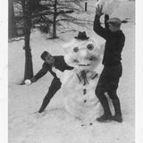 Zwei Männer toben um Schneemann herum