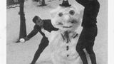Zwei Männer toben um Schneemann herum