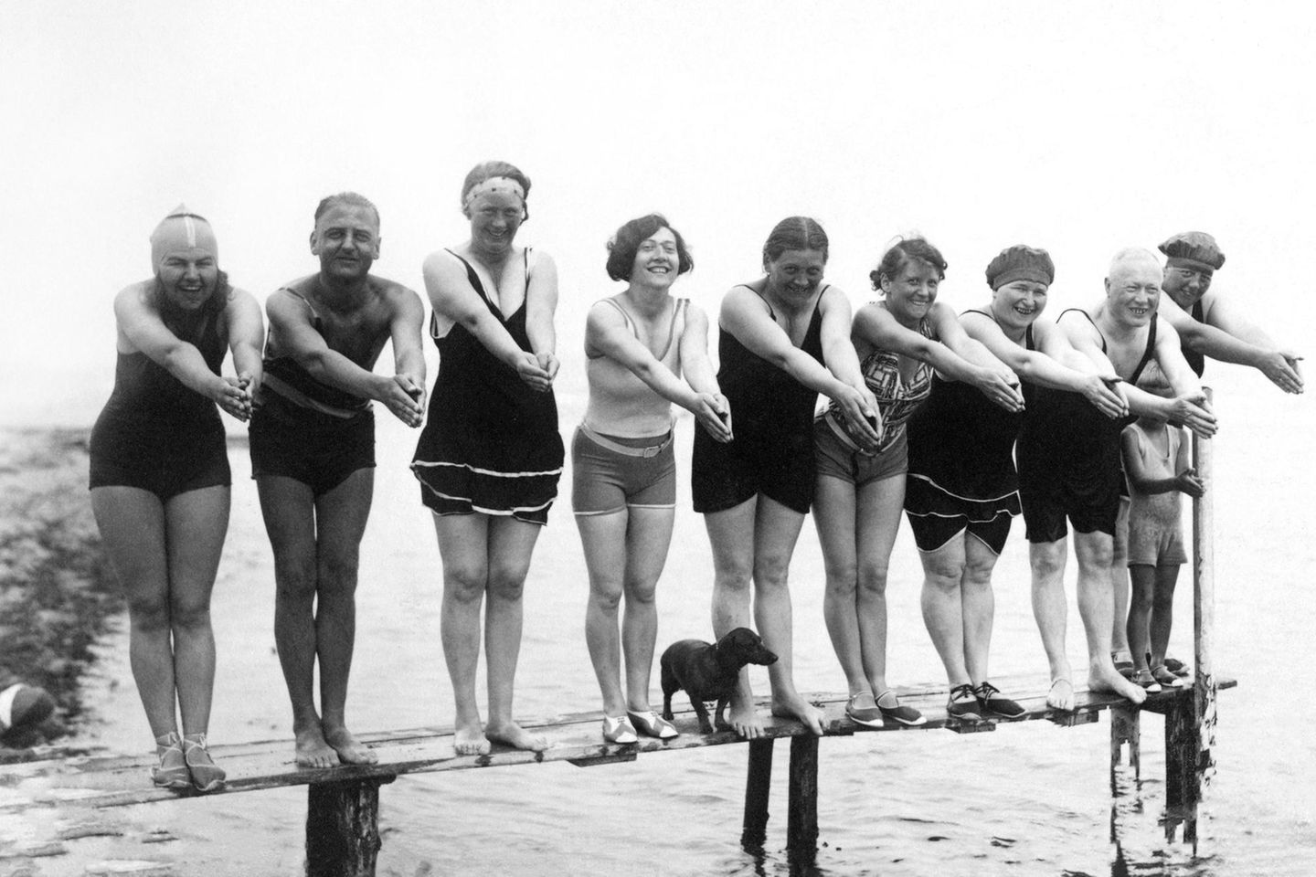 Phänomen Modehund Neun Männer und Frauen und ein Dackel posieren auf einem Bootssteg, 1920er Jahre Usedom