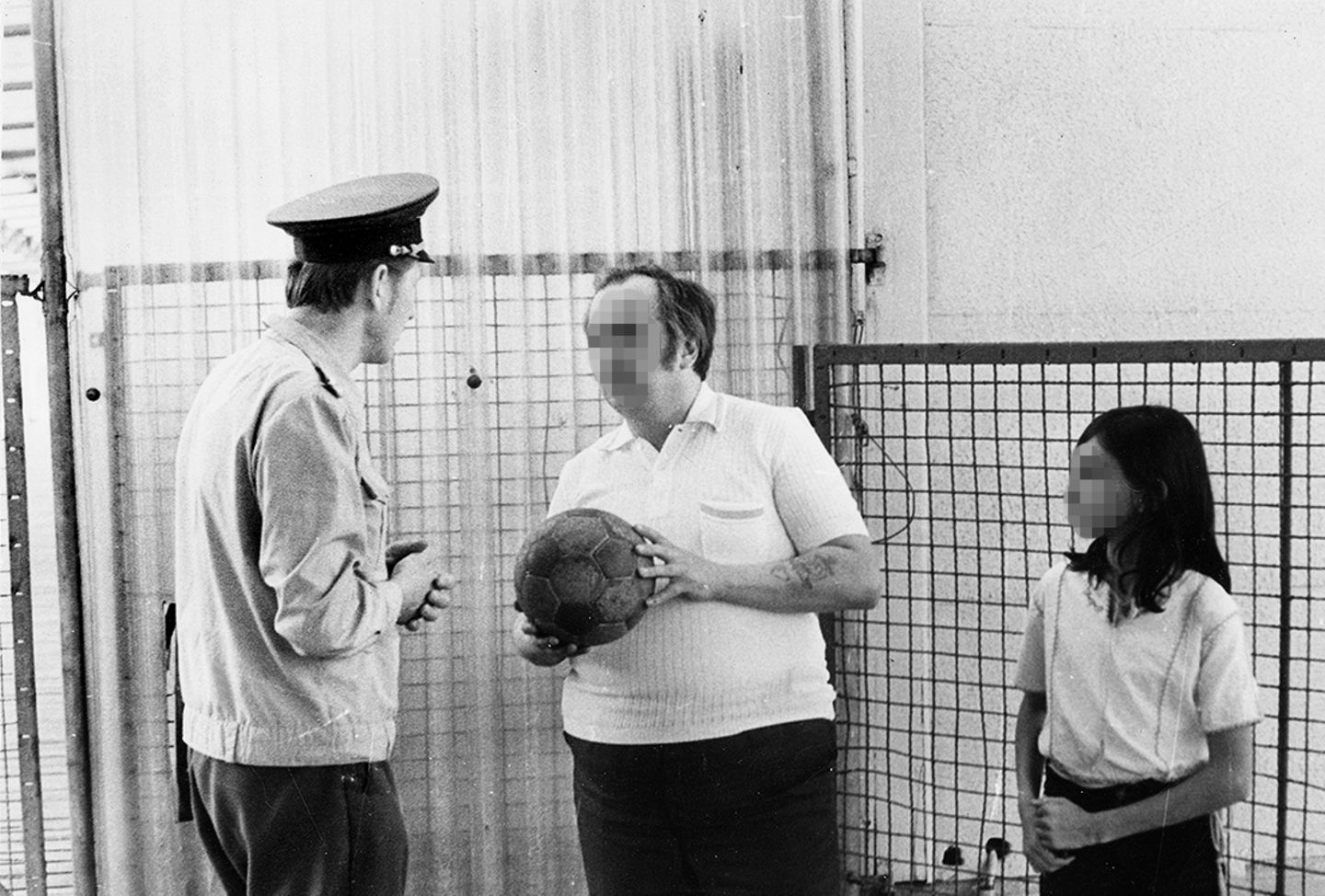Mann hält Fußball in der Hand und steht neben einem Beamten