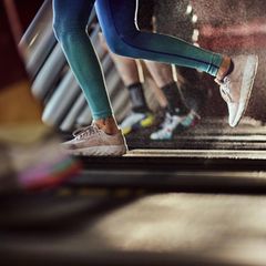 Unrecognizable athletic woman exercising on treadmill in a health club.