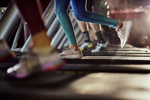 Unrecognizable athletic woman exercising on treadmill in a health club.