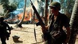 Soldat im Vietnamkrieg steht vor brennendem Dorf