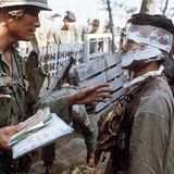 Ein Verwundeter mit Gesichtsverletzungen, der von einem Kameraden befragt wird