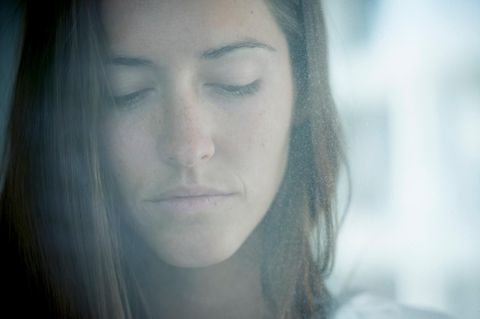 Eine Frau schaut traurig durch eine beschlagene Fensterscheibe