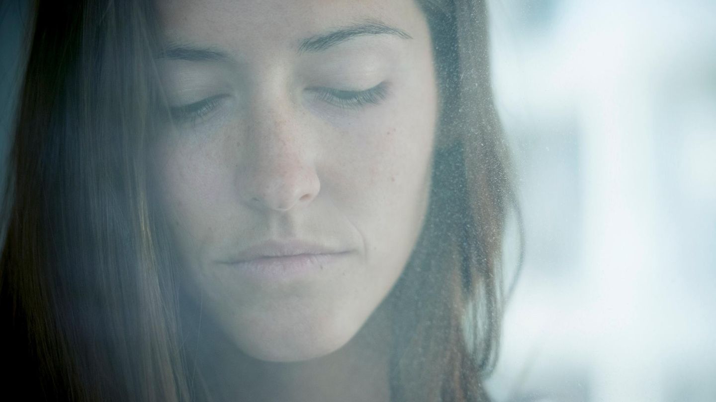 Eine Frau schaut traurig durch eine beschlagene Fensterscheibe Eine Frau schaut traurig durch eine beschlagene Fensterscheibe