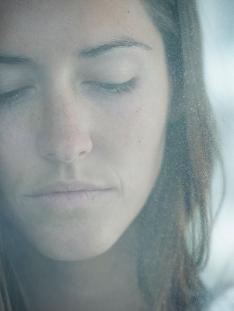 Eine Frau schaut traurig durch eine beschlagene Fensterscheibe