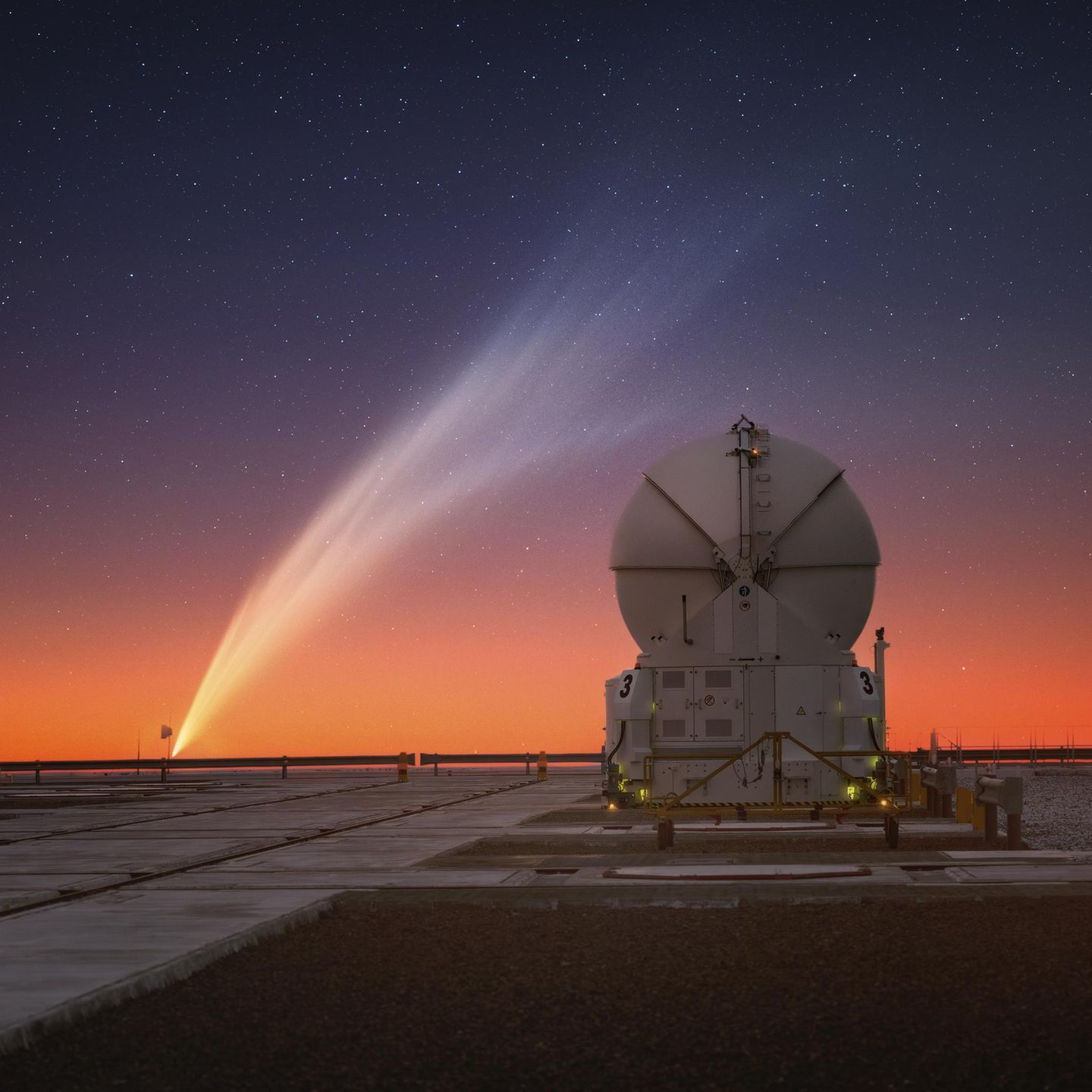 Wer saust durch den Nachthimmel Chiles? Im Vordergrund steht das Paranal Observatory in Chile. Im Hintergrund ist ein Kometenschweif zu sehen.