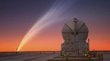 Im Vordergrund steht das Paranal Observatory in Chile. Im Hintergrund ist ein Kometenschweif zu sehen.