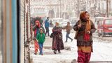 Personen laufen durch eine winterliche Stadtlandschaft