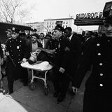 Malcolm X liegt verletzt auf Liege