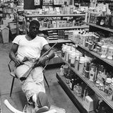 Mann sitzt mit Gewehr auf Stuhl in Geschäft