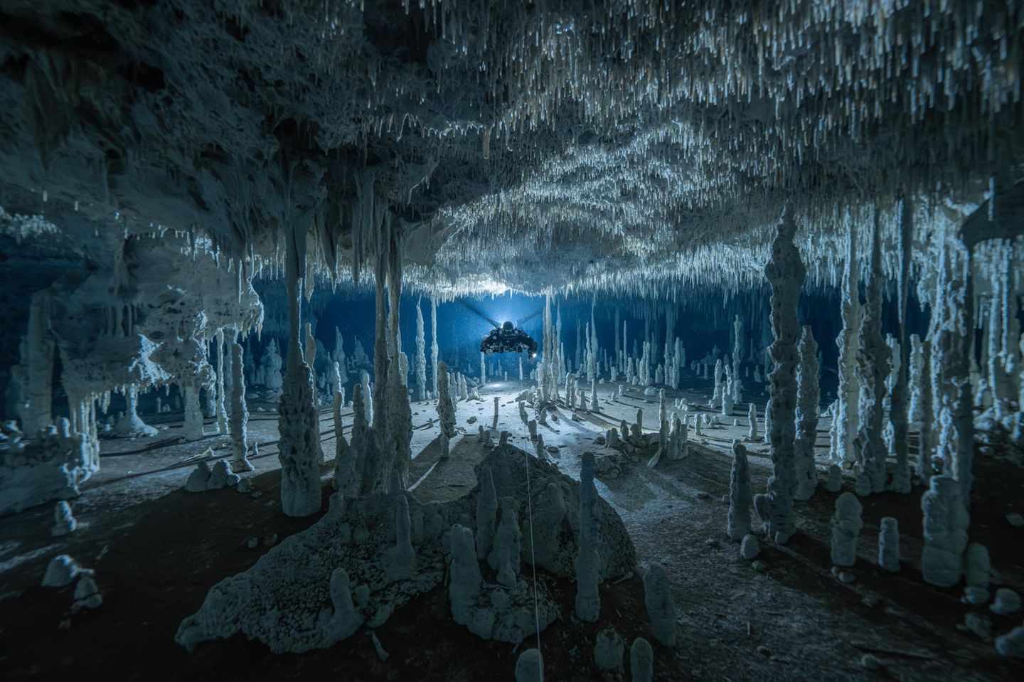 Ein Taucher scheint durch eine surreal anmutende Höhle auf der Halbinsel Yucatán, Mexiko, zu schweben. Das spezielle Atemgerät, ein Kreislauftauchgerät, ermöglicht es, ohne störende Blasen durch die zerbrechliche Welt der gefluteten Stalagmiten und Stalagtiten zu schwimmen.