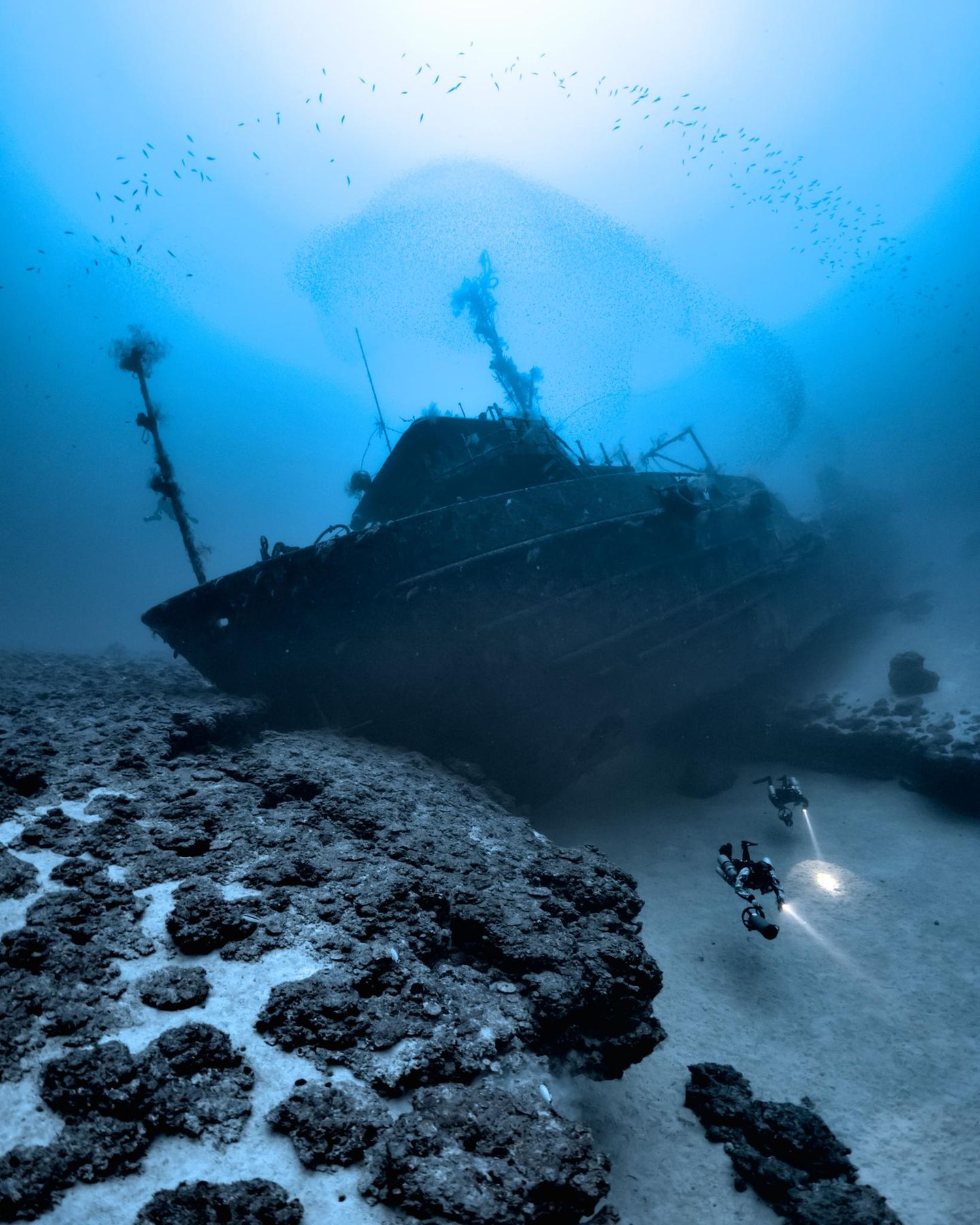 Im Roten Meer, Ägypten, gelang diese Aufnahme von einem gesunkenen Schiffswrack in knapp über 100 Meter Tiefe. Es liegt so auf zwei Riffen, dass die Taucher darunter durchtauchen können.