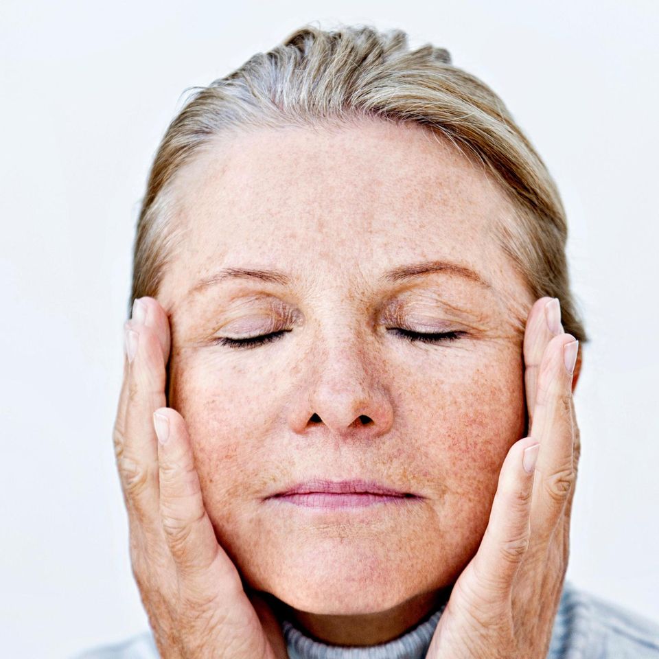 Frau fasst sich mit beiden Händen an den Kopf