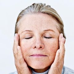 Frau fasst sich mit beiden Händen an den Kopf