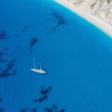 Lefkada, Greece. Remote white Egremni beach with lonely luxury yacht boat on the turquoise colored bay on Ionian Sea.