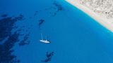 Lefkada, Greece. Remote white Egremni beach with lonely luxury yacht boat on the turquoise colored bay on Ionian Sea.