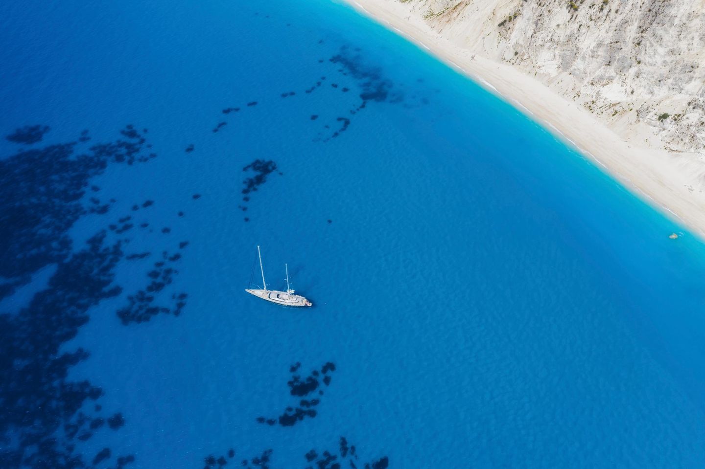 Lefkada, Greece. Remote white Egremni beach with lonely luxury yacht boat on the turquoise colored bay on Ionian Sea.