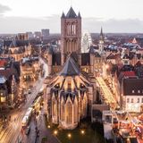 Man sieht die Stadt in der beginnenden Dämmerung. Straßenlichter leuchten. Der Blick fällt von oben auf St.-Bavo-Kathedrale.