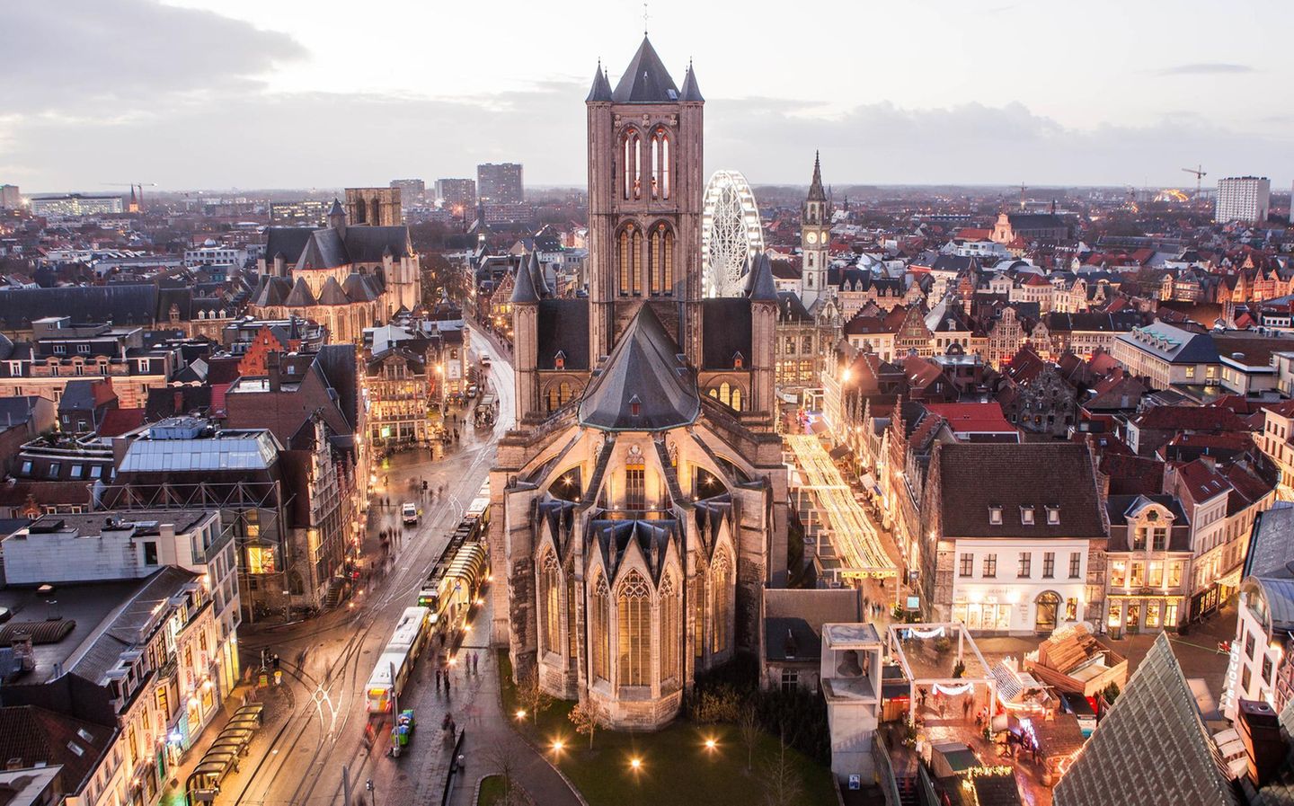 St.-Bavo-Kathedrale: Genter Altar bewundern Man sieht die Stadt in der beginnenden Dämmerung. Straßenlichter leuchten. Der Blick fällt von oben auf St.-Bavo-Kathedrale.