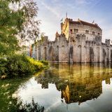 Die Gravensteen Burg ist in einem warmen Sommerlicht angestrahlt. Sie wirkt erhaben, eingebettet im Burggraben.