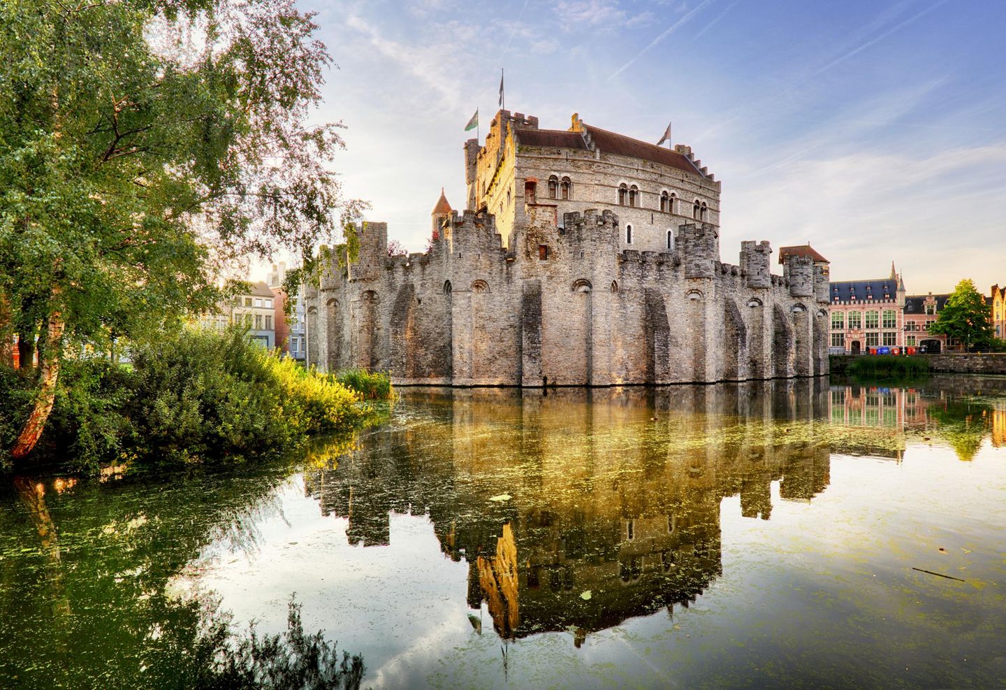 Die Gravensteen Burg ist in einem warmen Sommerlicht angestrahlt. Sie wirkt erhaben, eingebettet im Burggraben.