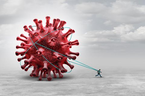 Ein Mann läuft und zieht an Schnüren ein riesiges Virus hinter sich her