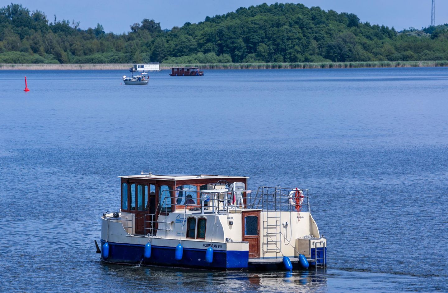 Mit einem Hausboot sind Urlauber auf der Kleinen Müritz in der Mecklenburgischen Seenplatte unterwegs