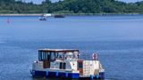 Mit einem Hausboot sind Urlauber auf der Kleinen Müritz in der Mecklenburgischen Seenplatte unterwegs