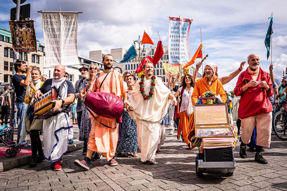 musizierende Menschen mit bunten Gewändern und Hare Krishna Fahnen 1.4993