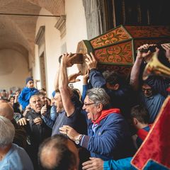Jubelnde Männer tragen Holzsäule