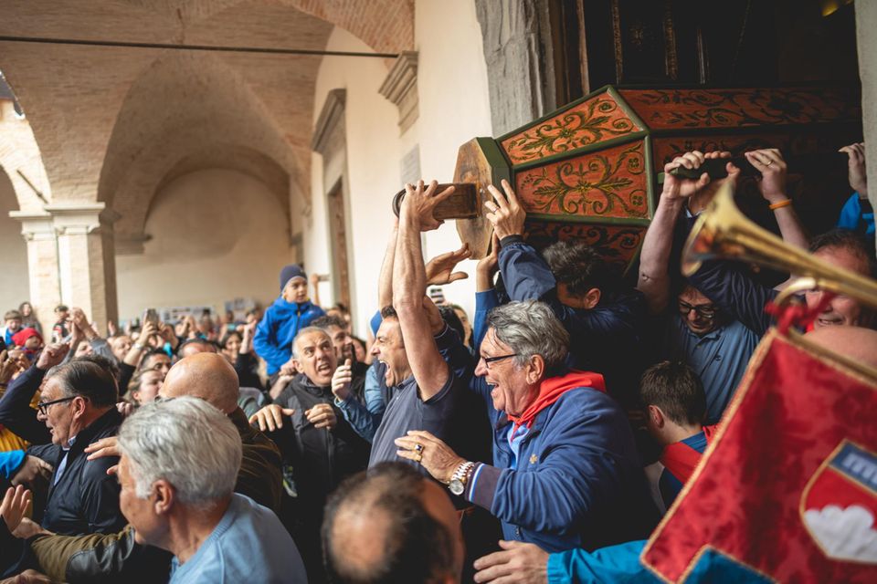 Jubelnde Männer tragen Holzsäule