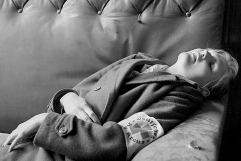 Eine junge Frau in einem Mantel, die Rot Kreuzbinde am Arm. liegt tot in einer Sofaecke, Schwarzweißfoto Eine junge Frau in einem Mantel, die Rot Kreuzbinde am Arm. liegt tot in einer Sofaecke, Schwarzweißfoto