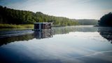 Schönes Revier in Brandenburg: Ein Hausboot fährt am frühen Morgen im Sonnenschein über die Havel
