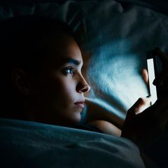 Frau schaut abends aufs Handy