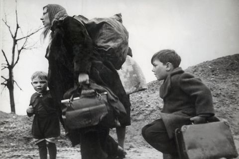 Schwarzweißfoto einer schwer bepackten Frau mit Kindern auf der Flucht im März 1945