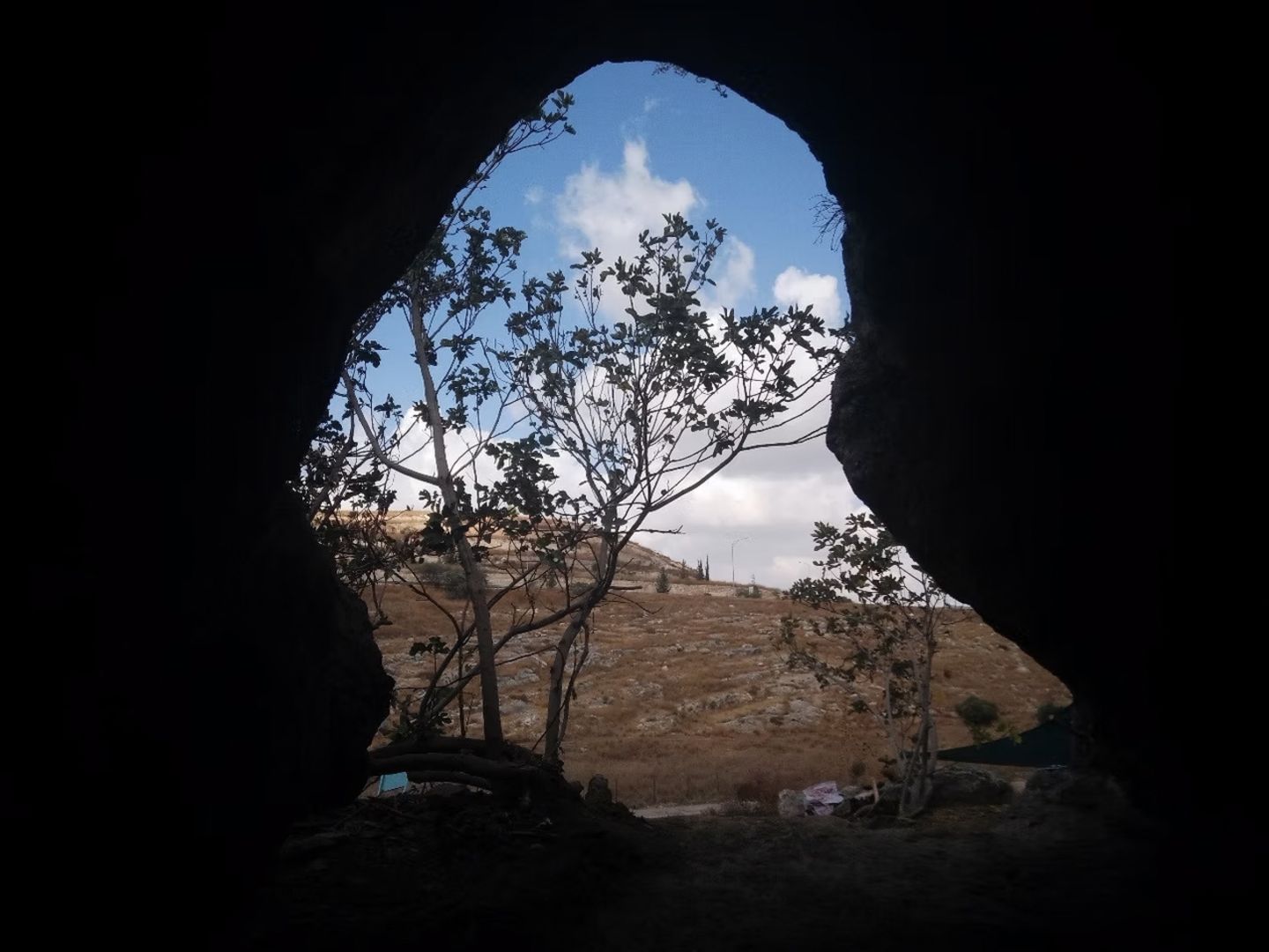 Blick aus einer dunklen Höhle in Israel ins Freie, auf eine karge Ebene und Himmel