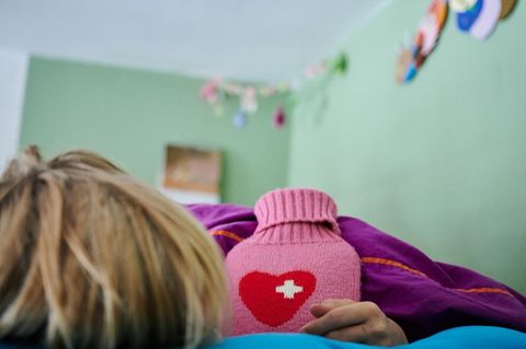 Kind mit Pims im Bett mit einer Wärmflasche