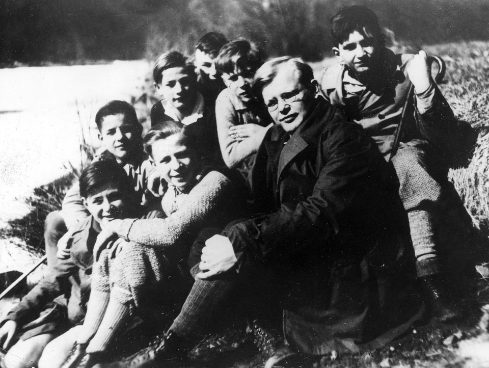 Dietrich Bonhoeffer sitzt umringt von Jugendlichen im Freien