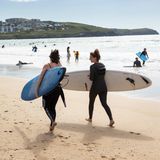 Zwei Surferinnen in Cornwall am Strand