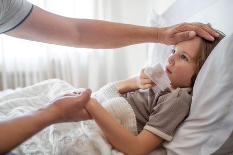 Ein an Grippe beziehungsweise Influenza erkranktes Kind liegt in einem Bett