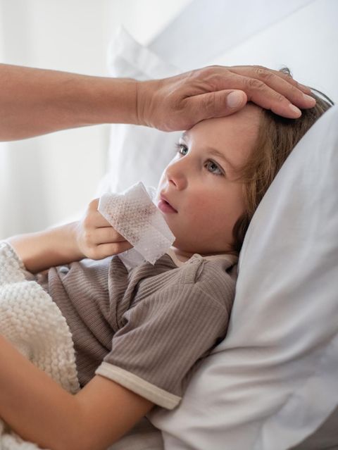 Ein an Grippe beziehungsweise Influenza erkranktes Kind liegt in einem Bett