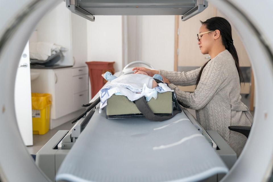 Eine Mutter legt ihr Baby in eine MRT-Apparatur Eine Mutter legt ihr Baby in eine MRT-Apparatur